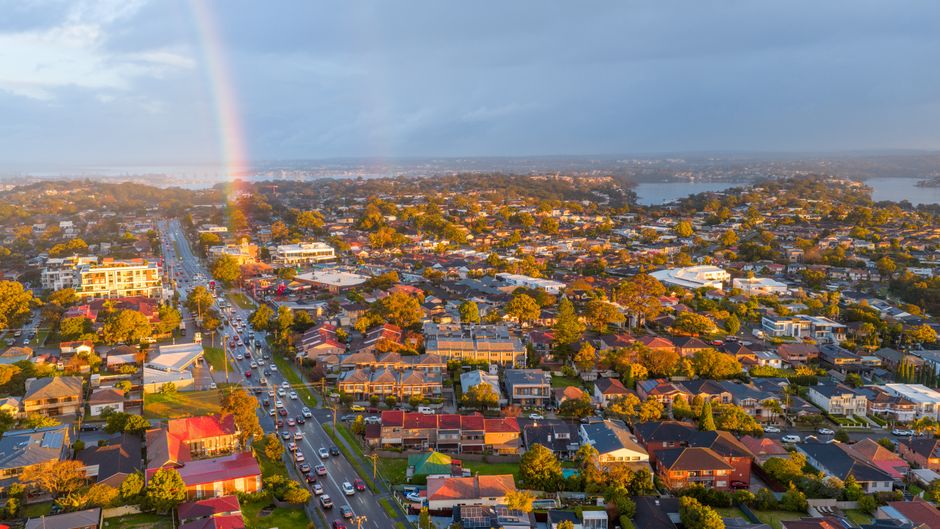 Stunning aerial view of suburban Sydney with a vibrant rainbow and clear skies.