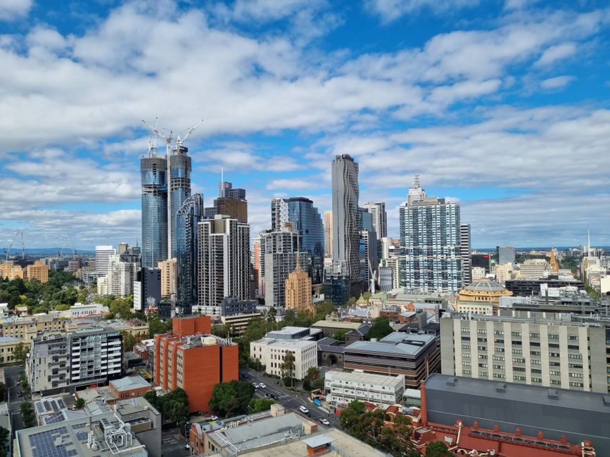 Panoramic view of Melbourne's urban skyline showcasing modern skyscrapers under a vibrant sky.